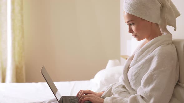 Woman Typing on Laptop in Bed.