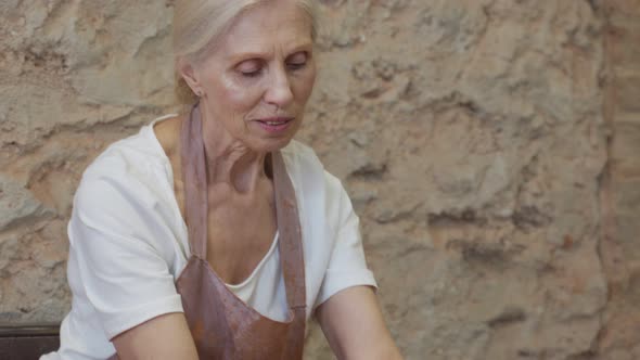 Senior Female Potter Sculpts a Clay Pot