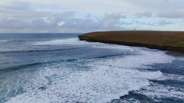 Slow motion aerial view of Birsay, Scotland with crashing waves.