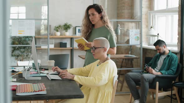 Female Colleagues Discussing Project on Computer in Office