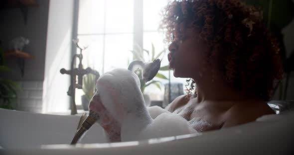 Funny Girl Sits in Bath Filled with Foam Holds Shower Singing Songs