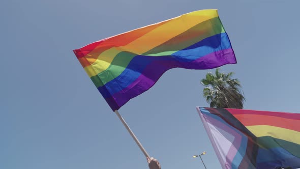 Slow motion of the rainbow flag waving during a pride parade in a city streets