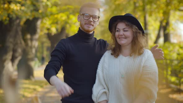 Portrait of Happy Young Couple Throwing Yellow Leaves in City Fall Park