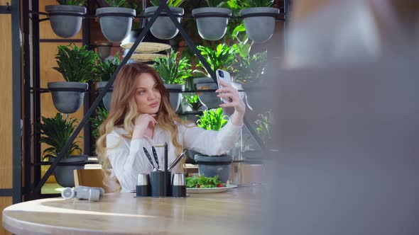 Young Woman Taking Selfie on Smartphone at Restaurant