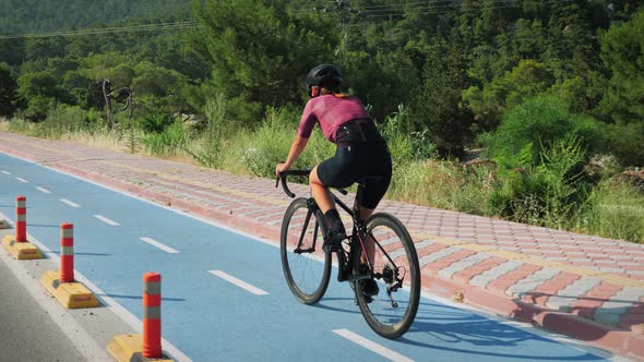 Woman in cycling apparel riding road bicycle on bicycle cycle lane