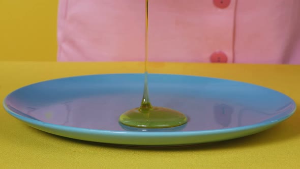 Honey Drips Onto the Plate. Golden Honey Flows Down on a Saucer, Close-up.