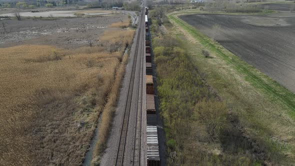 Train waiting on tracks in autumn through agriculture fields with standing water on each side.