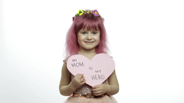 Child Girl Princess Holds Pink Paper Heart with Text About Mother. Mother's Day