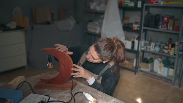 Woodworker checking quality of wooden lamp in workshop