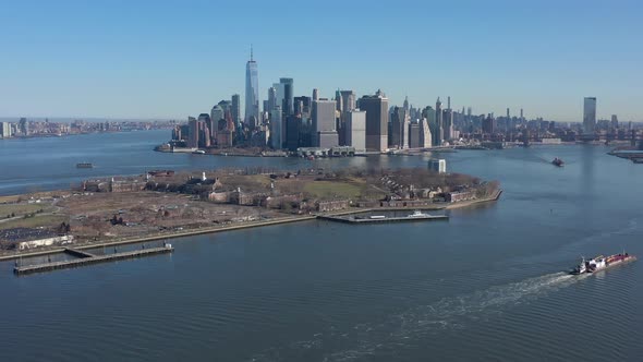 An aerial view of New York harbor on a sunny day with clear blue skies. The camera truck right, high