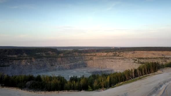 Huge Grey Mining Quarry Against Small Town Silhouette