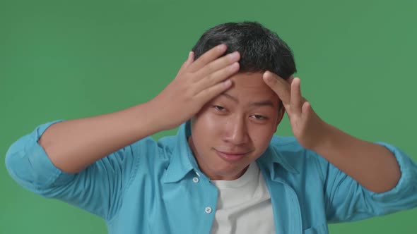 Young Asian Boy Touching His Hair While Looking At Camera Like A Mirror On Green Screen In Studio