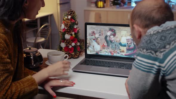 Festive Couple Talking to Family on Video Call at Christmas Dinner