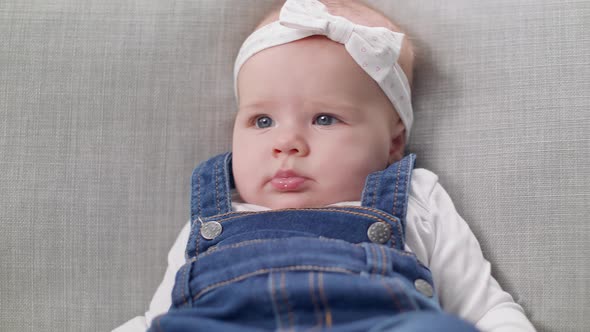 Little Baby Girl Sitting on a Sofa in the Living Room