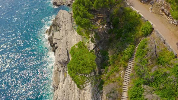 Aerial View on Turquoise Sea with Rocky Shore and Steps in Petrovac Montenegro