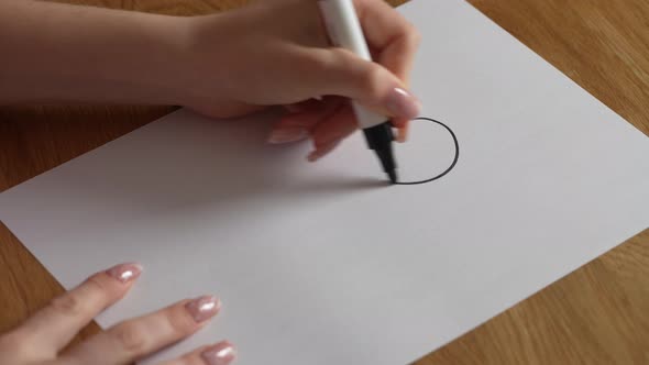 Girl on a white sheet draws a question mark with a black marker, close up