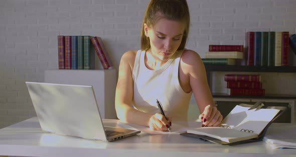 Front View of a Young Woman Works in an Office She Makes Notes on Paper and Enters Data Into a