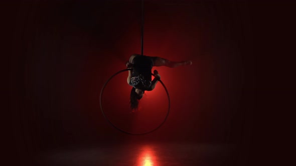 Aerial Acrobat in the Ring. A Young Girl Performs the Acrobatic Elements in the Air Ring on Red