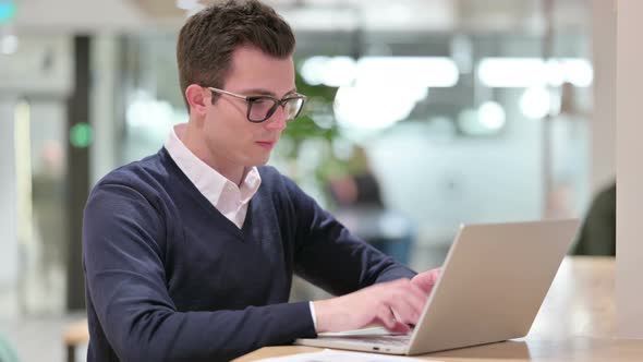 Young Businessman with Laptop Pointing at the Camera 