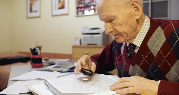 Senior Businessman Reading Contract with Magnifying Glass