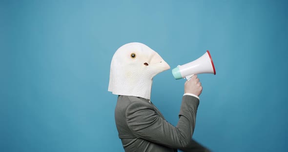Guy in Gray Suit with Pigeon Mask on Blue Background Talking on the Megaphone
