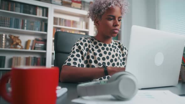 Young African American Woman Student Typing on Laptop Keyboard Sits in Office
