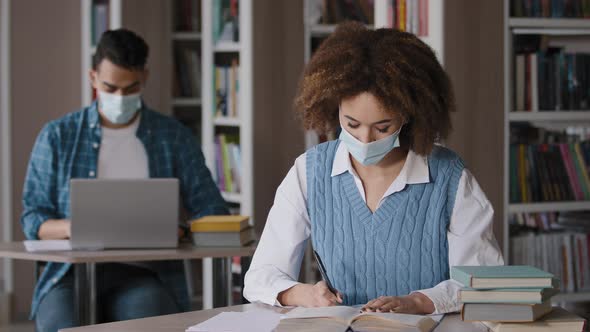 Two Students in Protective Mask Sitting in Classroom at University Library Doing Homework Exam