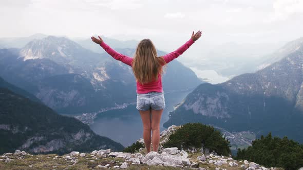 Back View of Young Woman Rise Her Hands Enjoying Amazing View of Lake in Mountains