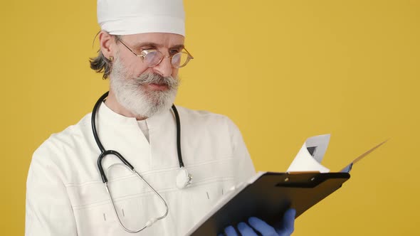 Senior Doctor with Notepad on Yellow Background