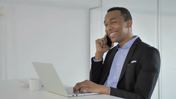 Positive Casual AfroAmerican Businessman Talking on Phone Negotiating with Customer