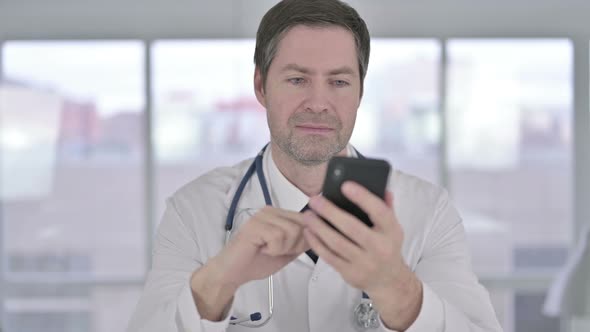 Portrait of Middle Aged Doctor Using Smartphone in Office