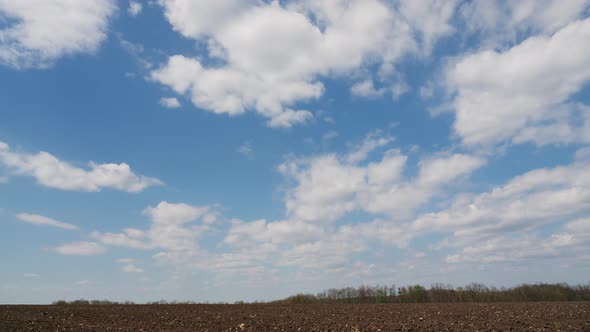 Timelapse Clouds Form in the Blue Sky Over an Agricultural Field