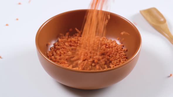 Red lentils in a bowl on white background. Healthy organic food diet concept.