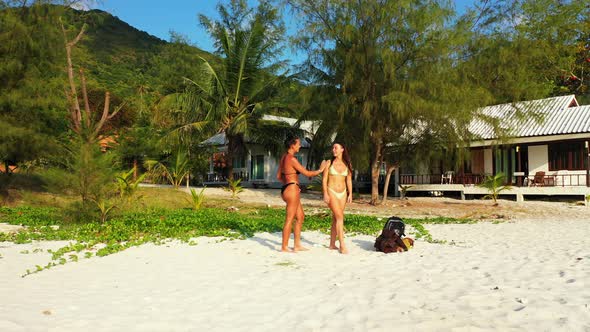 Sexy beauty models travelling spending quality time at the beach on clean white sand and blue backgr