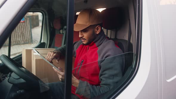 Young Indian Man Courier Using Tablet While Delivering Parcel