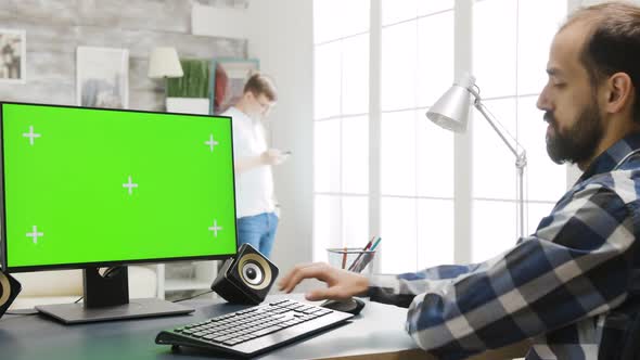 Person Working on PC Display with Green Screen in Cozy Bright Living Room