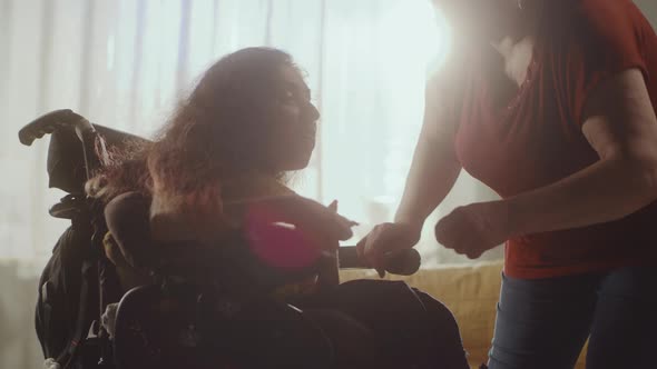 Caregiver Helping Woman to Sit in a Wheelchair