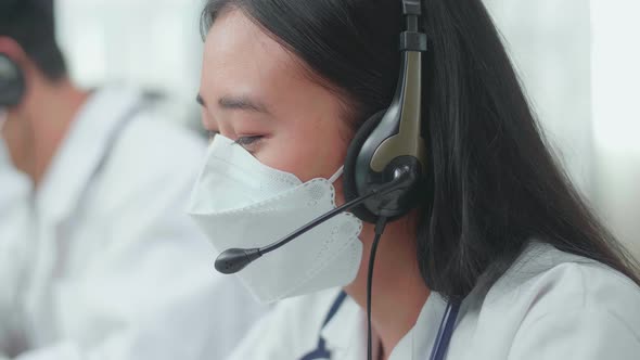 Close Up Of An Asian Woman Doctor In Masks Working As Call Centre Agent And Speaking To Customer