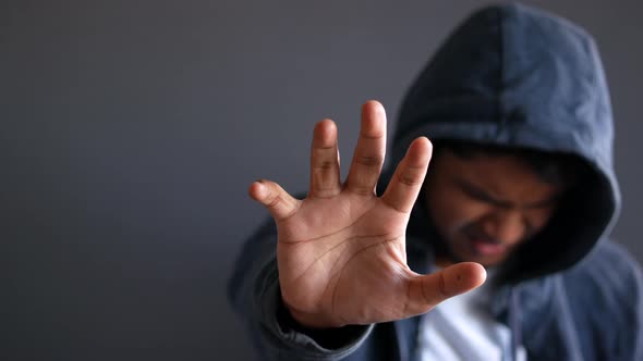 Sad Man in Hood Cover Face with Hands Isolated in Black