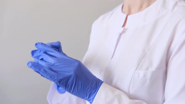 A Female Doctor Surgeon in White Uniform Puts Off Blue Gloves