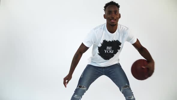 Slow Motion shot of an African American dribbling a basketball. Shot in a studio with a white backgr