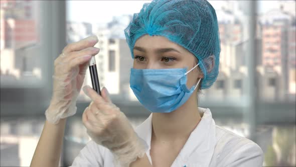 Female Medical Worker Looking at Blood Test Tube