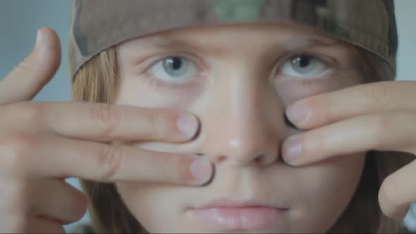 Portrait of young boy in soldier clothing putting on black face paint