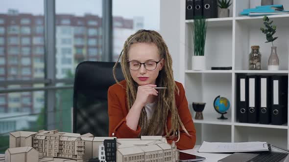 Woman with Dreadlocks Looking at Camera in Modern Design Office Agency