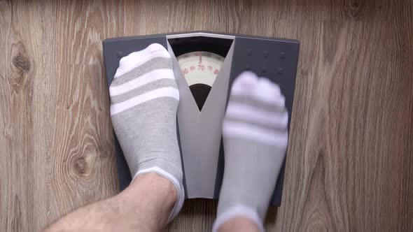 Man steps on the mechanical floor scales for checks his weight.