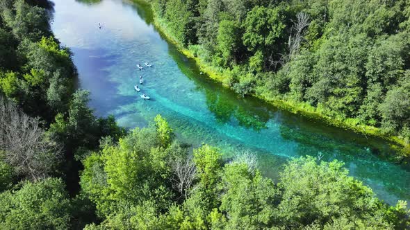 Group of people is rafting. Clouds are reflected in mirror-like surface of river