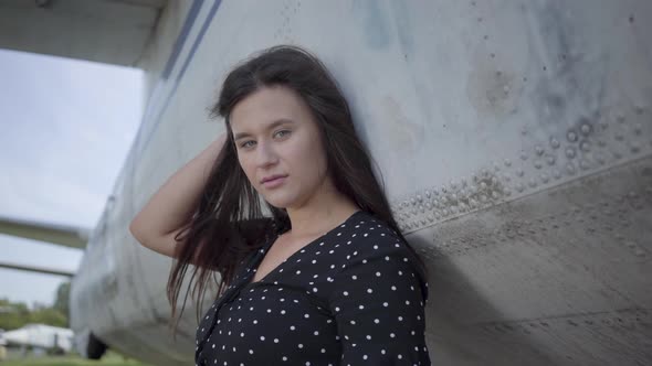 Confident Adorable Young Brunette Woman Dressed in a Black Dress Looking at the Camera in Front