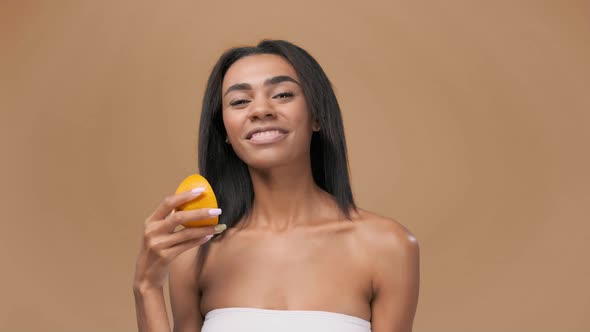 Pretty Smily African American Young Woman Winking at Camera with a Frech Half of an Orange