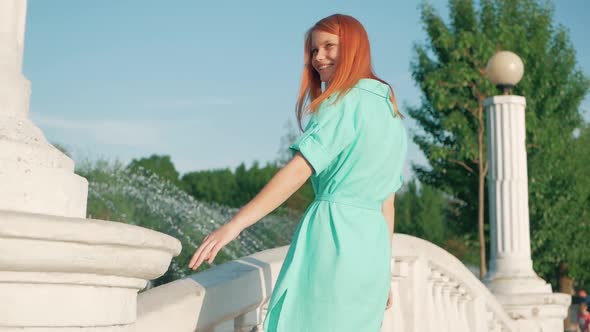 young beautiful girl walking in the spring or summer park. Passes along the bridge holding a hand on