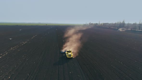 Tractor in the Large Brown Field Prepares the Soil for Sowing. Flight Around